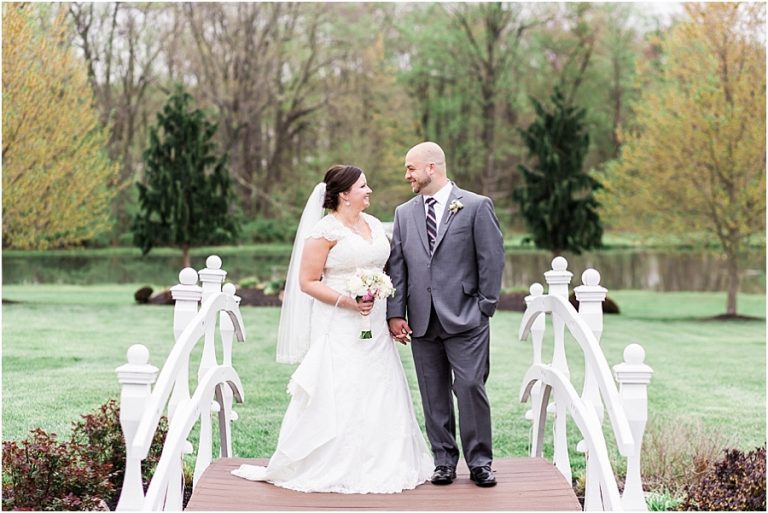 bride and groom hold hands on a white bridge at chester county wedding venue